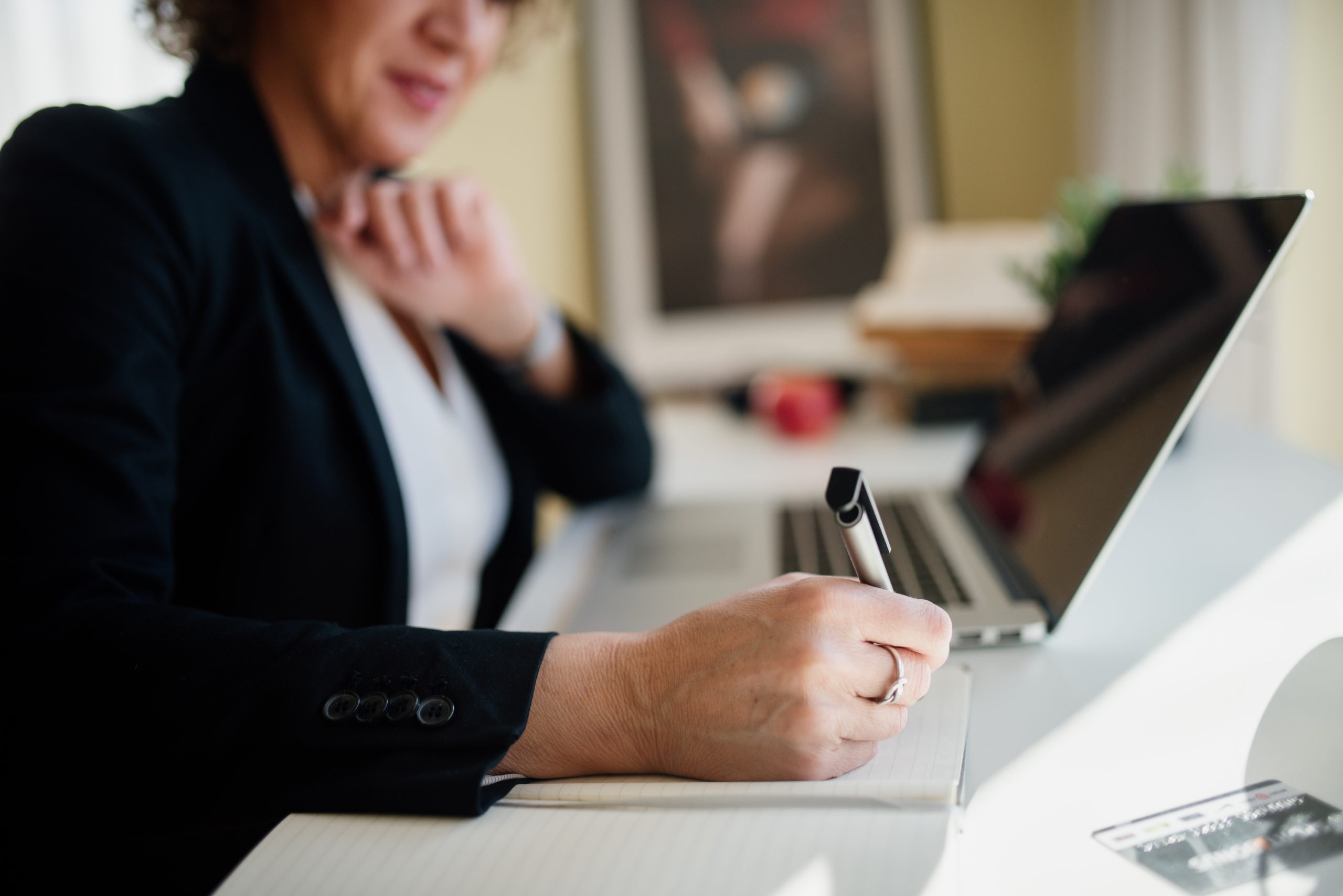 Business professional taking notes beside a laptop during a Shopware data architecture planning meeting