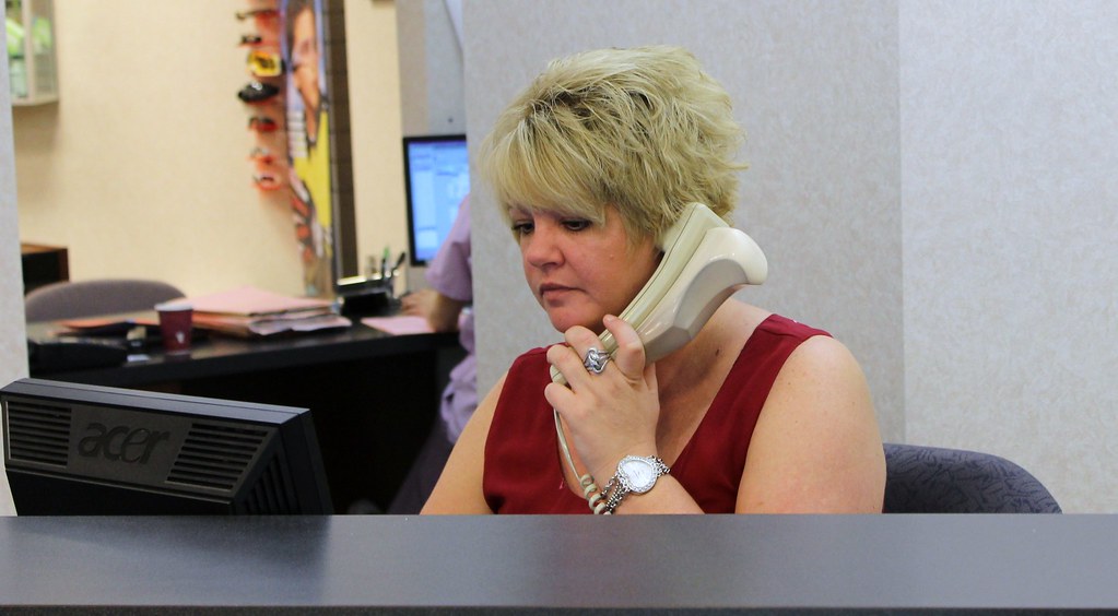 Receptionist answering a customer call while managing appointments on a computer